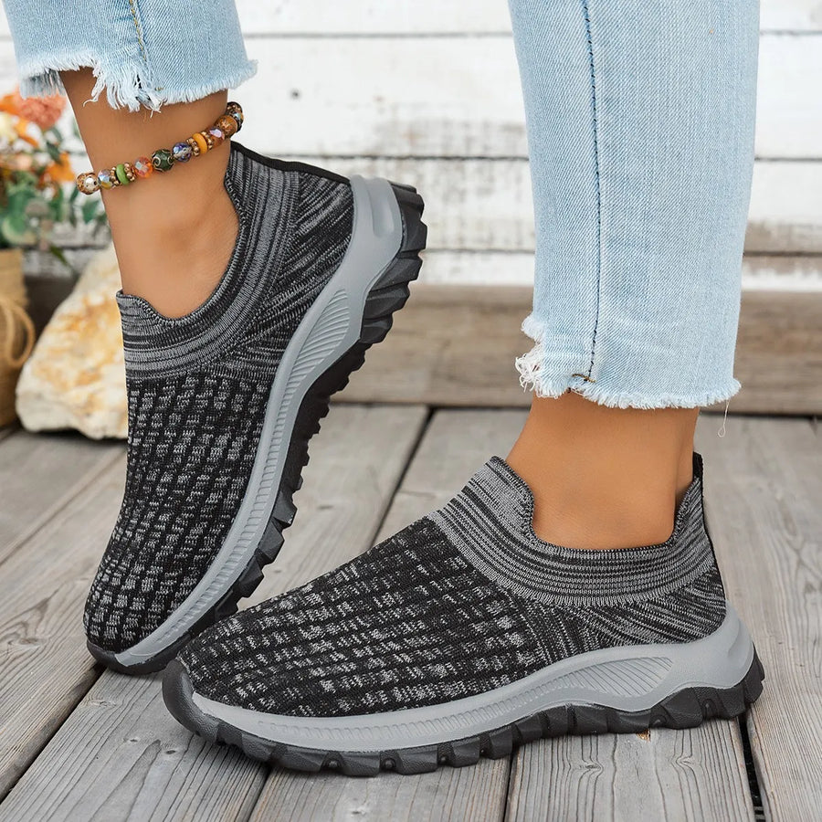 Textured knit slip-on sneakers in black with grey accents and a grey sole.