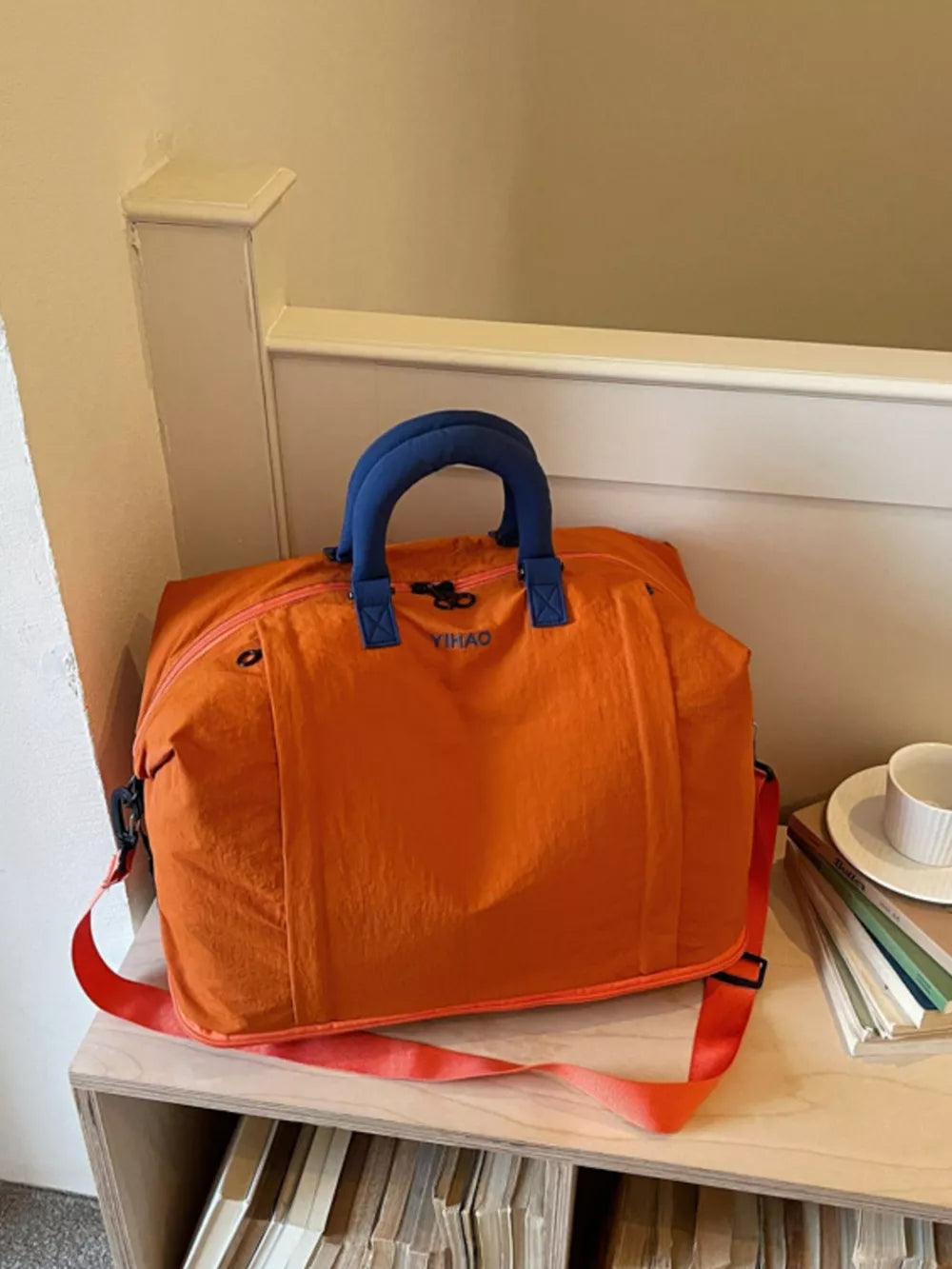 Spacious orange Oxford cloth travel bag with blue handles and strap, perfect for toiletries.