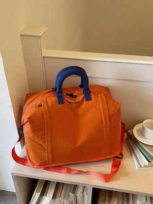 Spacious orange Oxford cloth travel bag with blue handles and strap, perfect for toiletries.