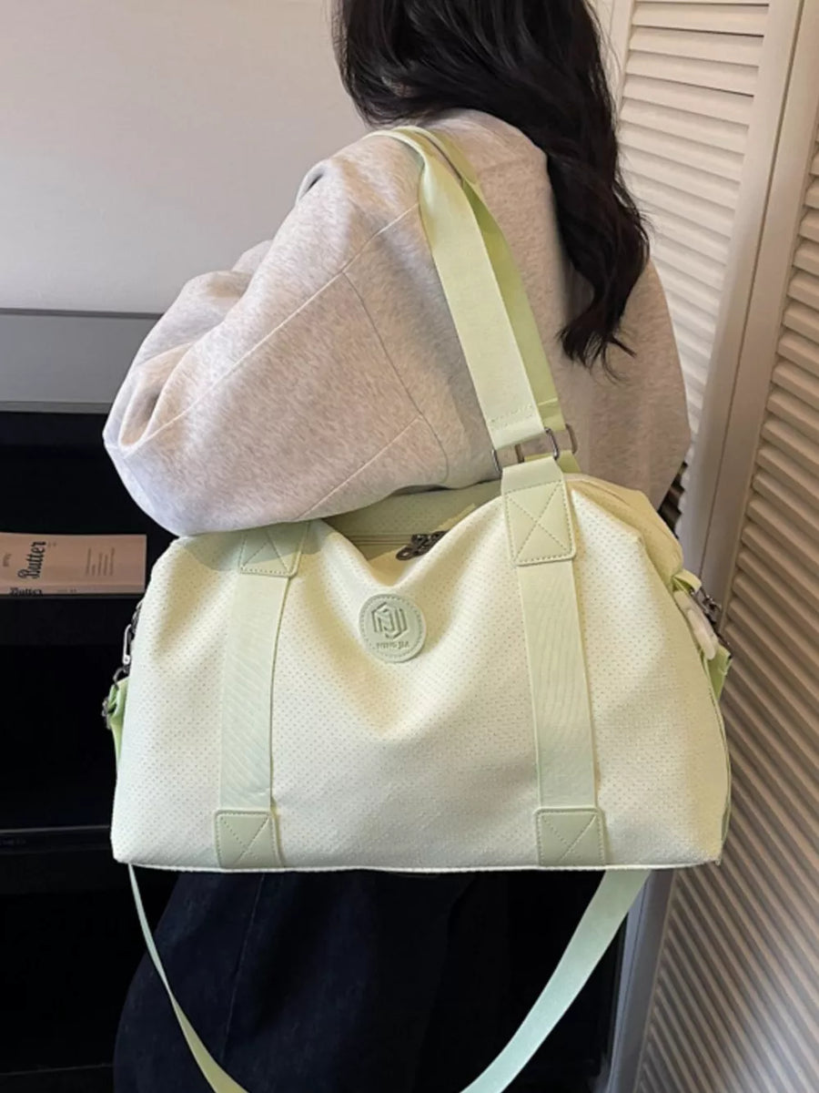 Chic perforated large duffle bag in light green with adjustable strap and logo detail.