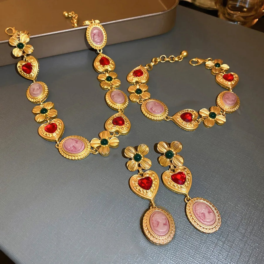 Gold bracelet with heart, cameo and floral charms, red and green stones