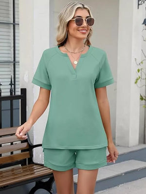 Green relaxed two-piece set with v-neck top and shorts, featuring pockets.