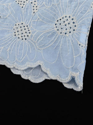 Light blue cotton eyelet fabric with white floral embroidery and scalloped hem.