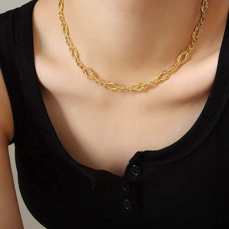 Gold heart link chain necklace with intricate knot details on brass.