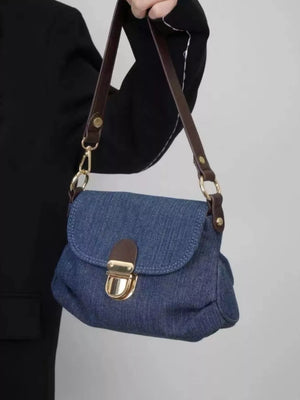 Mini denim shoulder bag with brown leather strap and gold clasp closure.