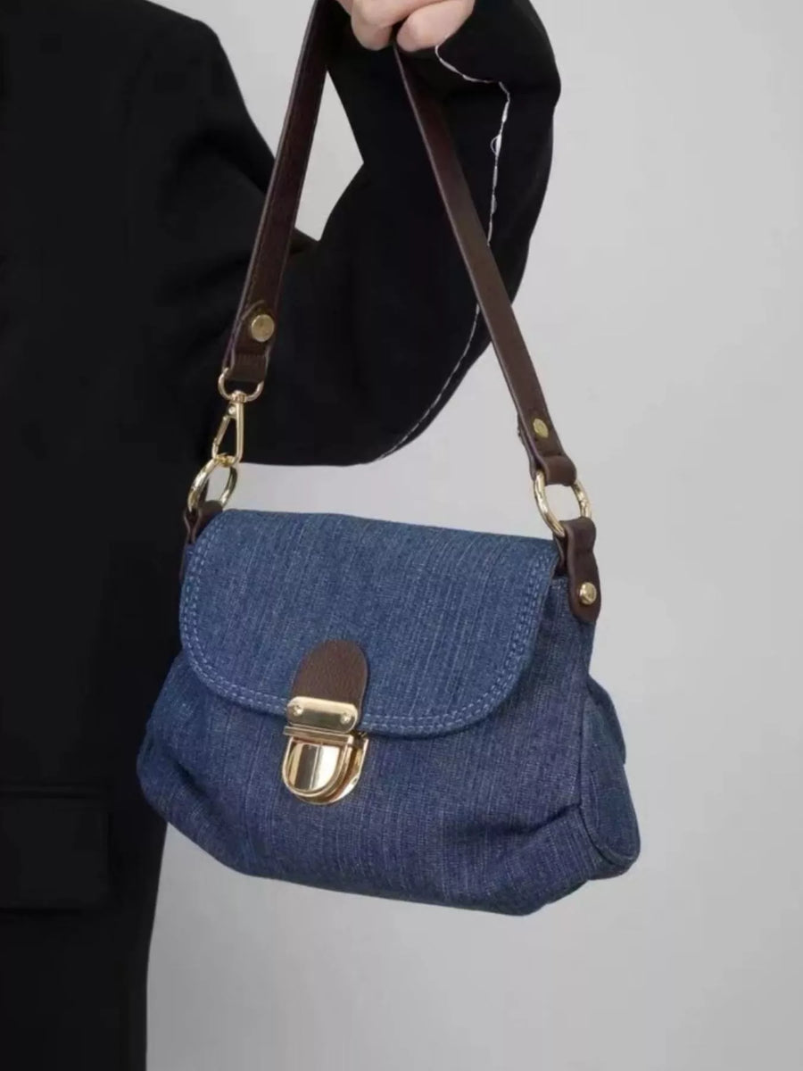 Mini denim shoulder bag with brown leather strap and gold clasp closure.