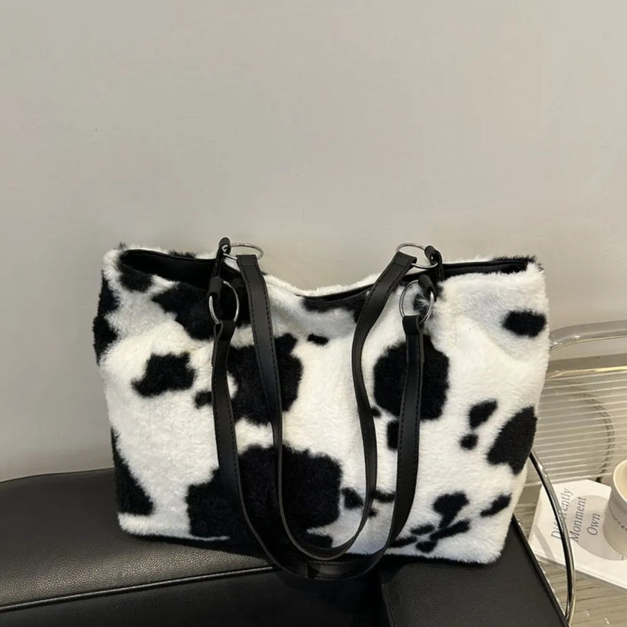 Cowhide print faux fur shopper bag with black faux leather straps and silver hardware.