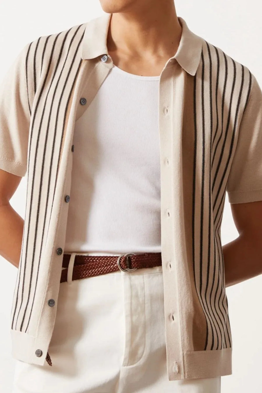 Beige knit polo shirt with vertical stripes, buttoned front, short sleeves, worn over a white tank top.