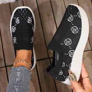 Black mesh slip-on sneakers with white geometric pattern and white soles.