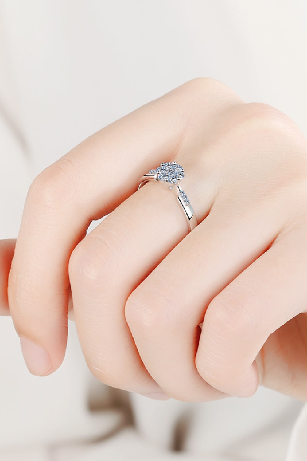 Silver engagement ring with a floral cluster moissanite center and pave band.