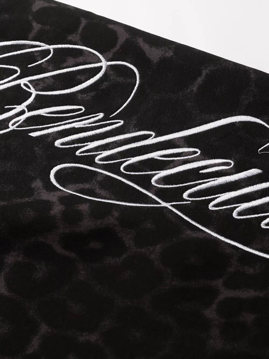 Black leopard print sweatpants with white script embroidery detail.