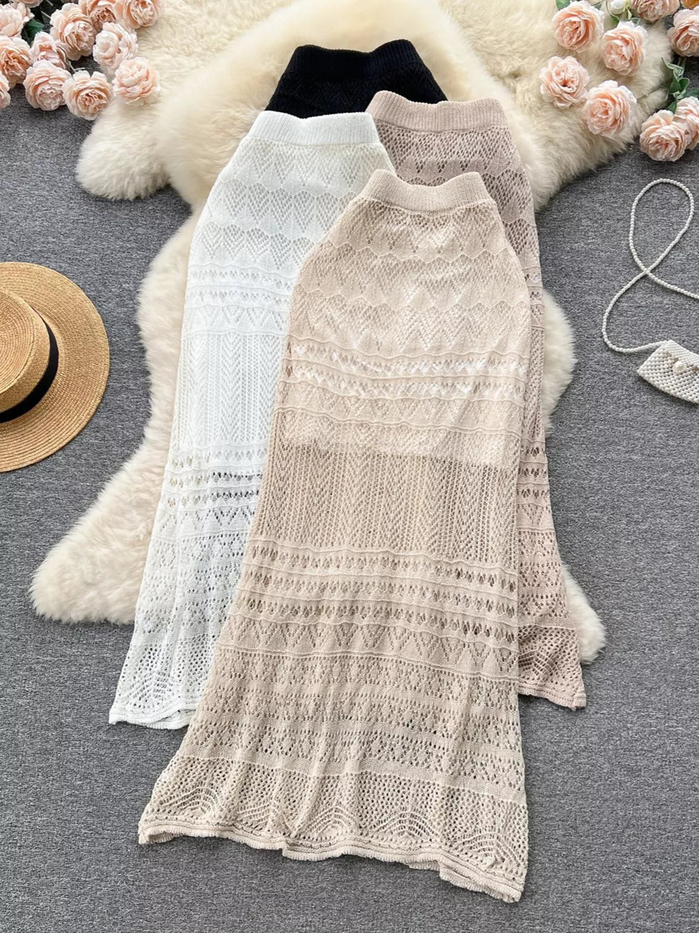 Intricately woven openwork maxi skirts in black, white, and apricot, featuring delicate knit patterns.