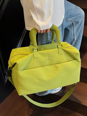 Duffel bag in bright green nylon with padded handles and a crossbody strap.