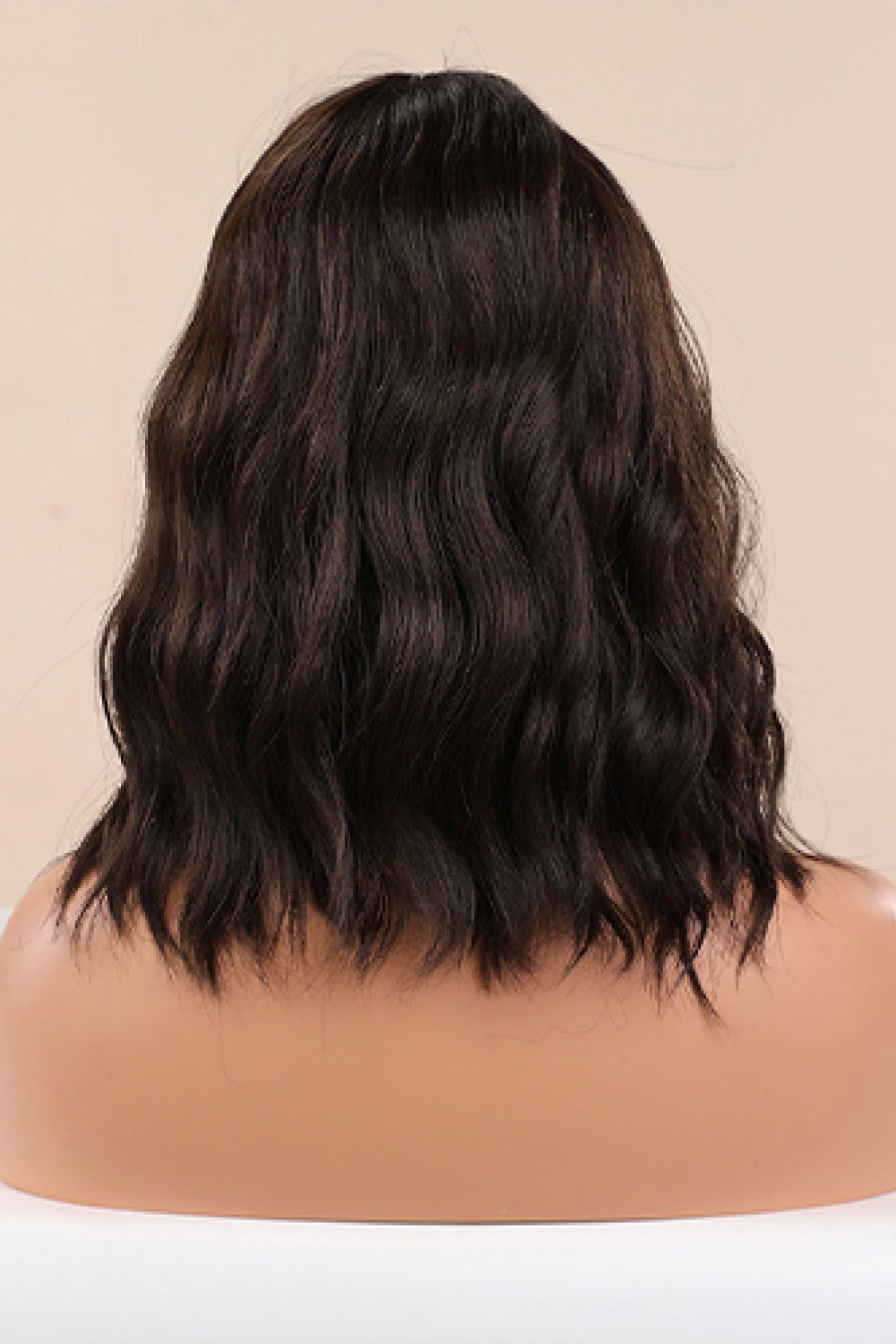Textured black bob wig with loose waves and a fringe.