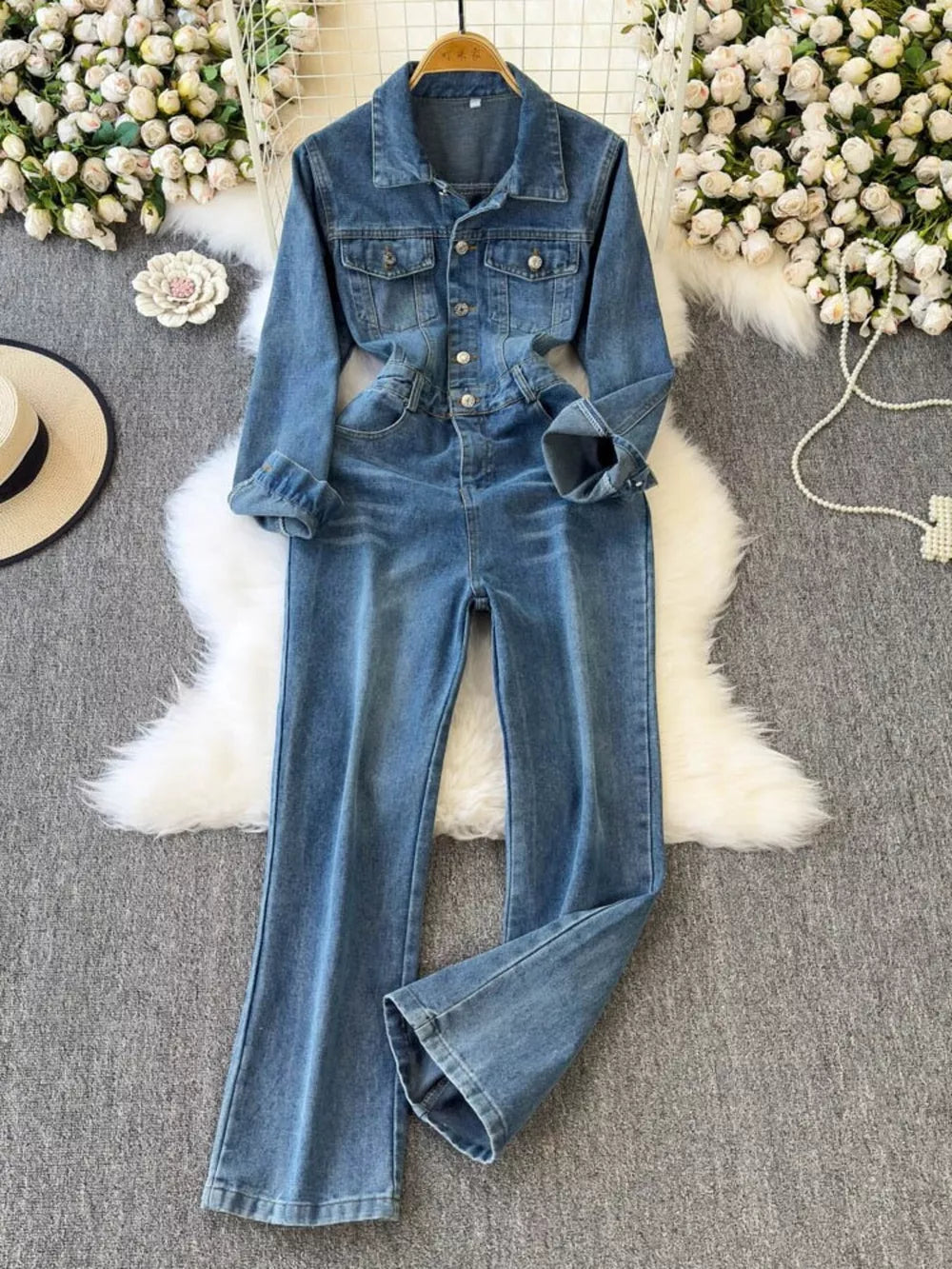 Chic buttoned denim jumpsuit with pockets, collared, long sleeves, and flared legs.
