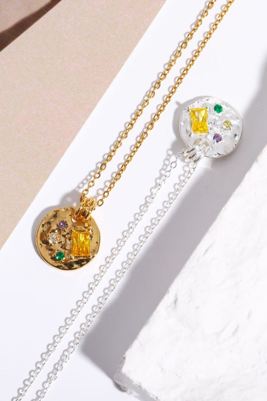 Gold and silver necklaces with textured disc pendants and colorful gemstone accents.
