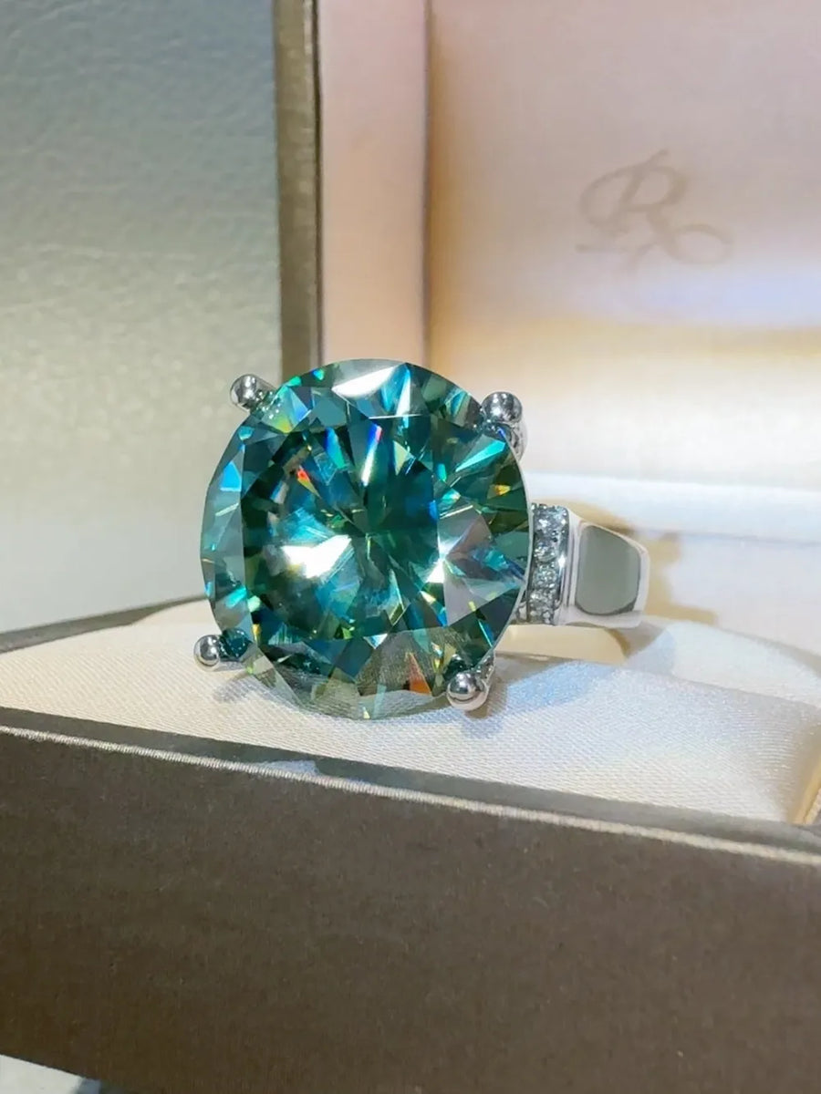 Prismatic teal statement ring with a large faceted gemstone and small accent stones.