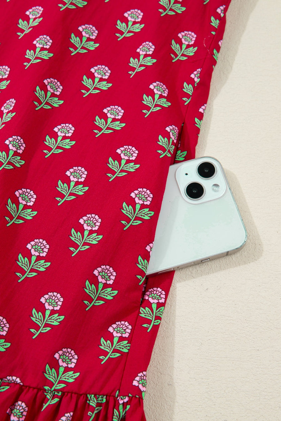 Red floral mini dress with pink flowers, green leaves, and a pocket holding a phone.