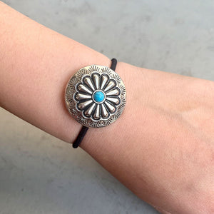 Southwestern medallion hair tie with turquoise center on black elastic band.