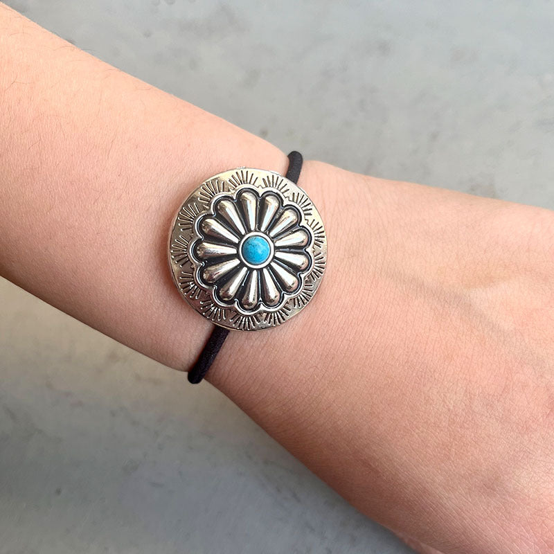 Southwestern medallion hair tie with turquoise center on black elastic band.