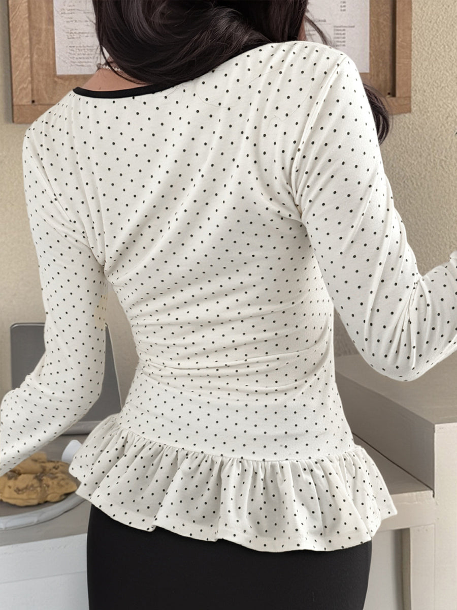 White polka dot long-sleeve t-shirt with ruffled hem and black trim neckline.