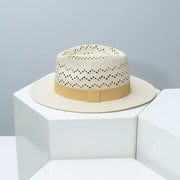 Straw boater hat in natural with ochre ribbon and open weave crown detail.