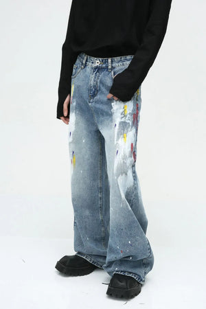 Painterly Wash Wide-Leg Denim Trousers in medium wash feature artistic paint splatters and a relaxed fit.