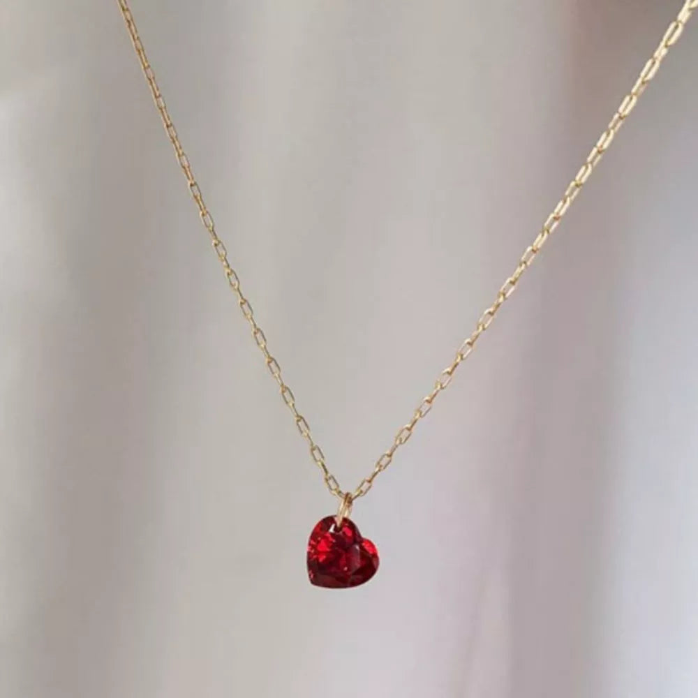 Gold chain necklace with a red heart-shaped zircon pendant.