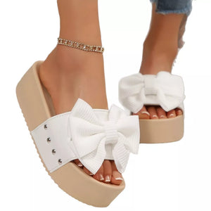 White ribbed bow platform sandals with studded detail and tan sole.