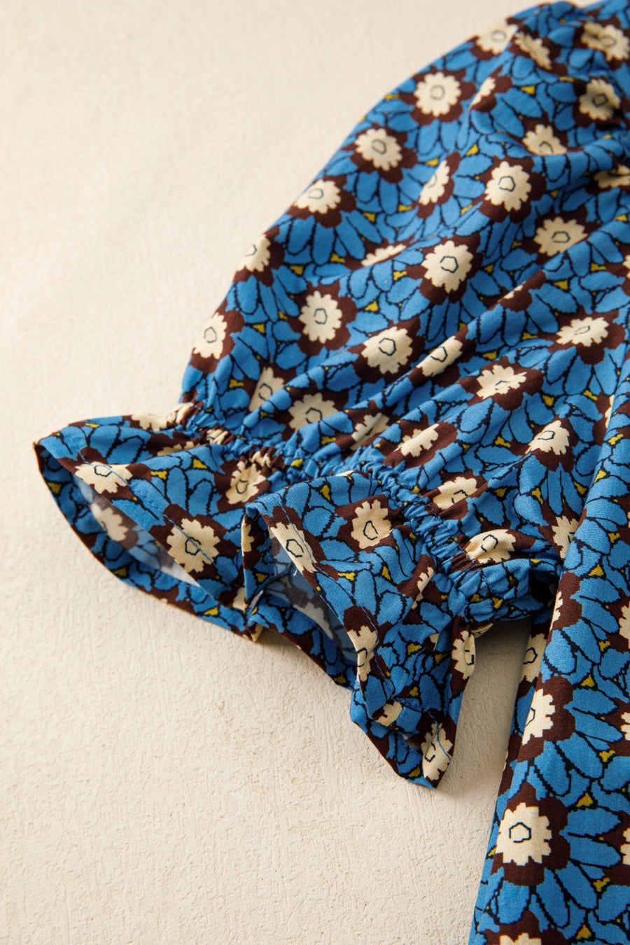 Floral V-neck puff sleeve blouse in blue with white and brown floral print and ruffled cuffs.