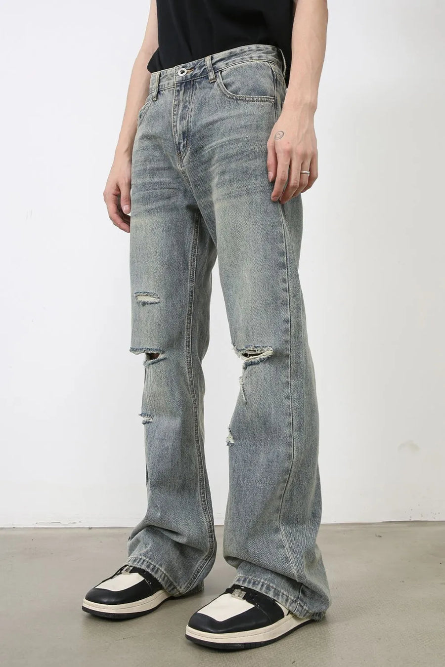 Distressed flare jeans in medium wash denim with raw-cut knee details.