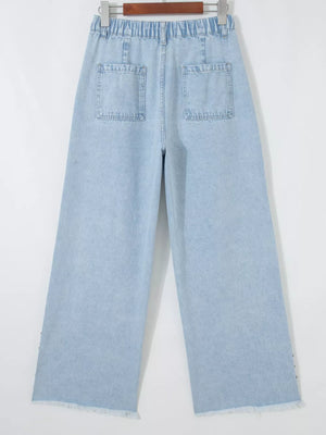 Light wash denim wide-leg jeans with studded side slits and raw hem.
