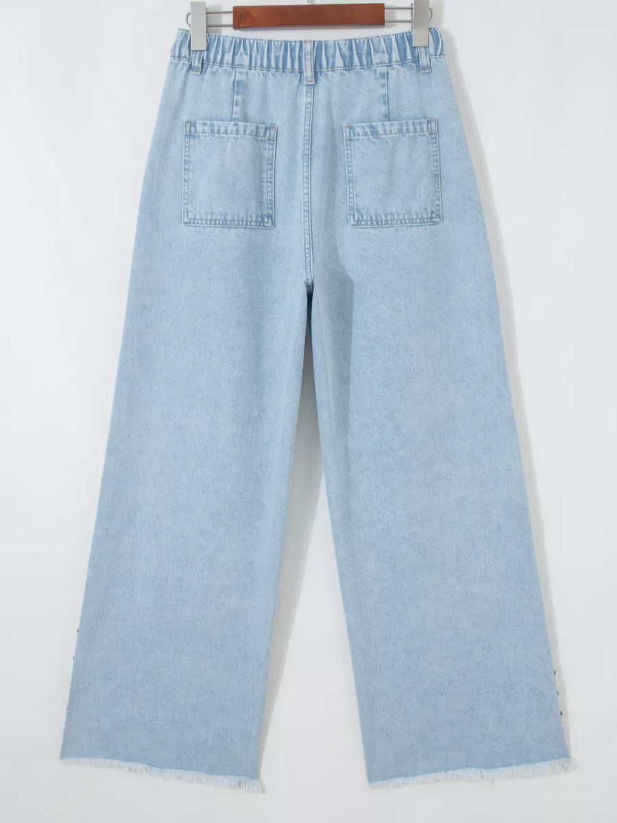 Light wash denim wide-leg jeans with studded side slits and raw hem.