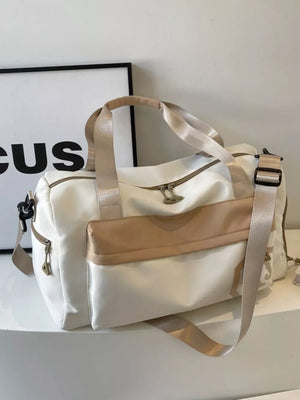 Off-white Oxford cloth duffel bag with tan accents and detachable strap.