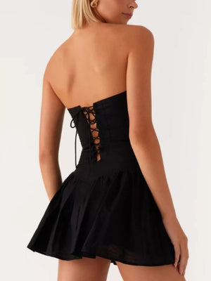 Black ruffled tube dress with lace-up back detail and flared skirt.