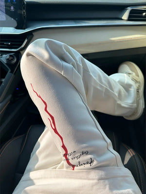 Men's cream sweatpants with red graphic detail and text graphic.
