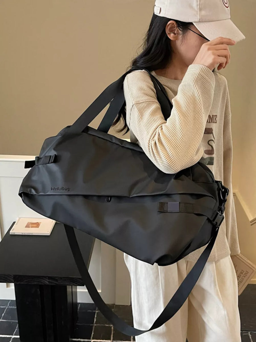 Black Oxford cloth travel bag with adjustable shoulder strap and buckle details.