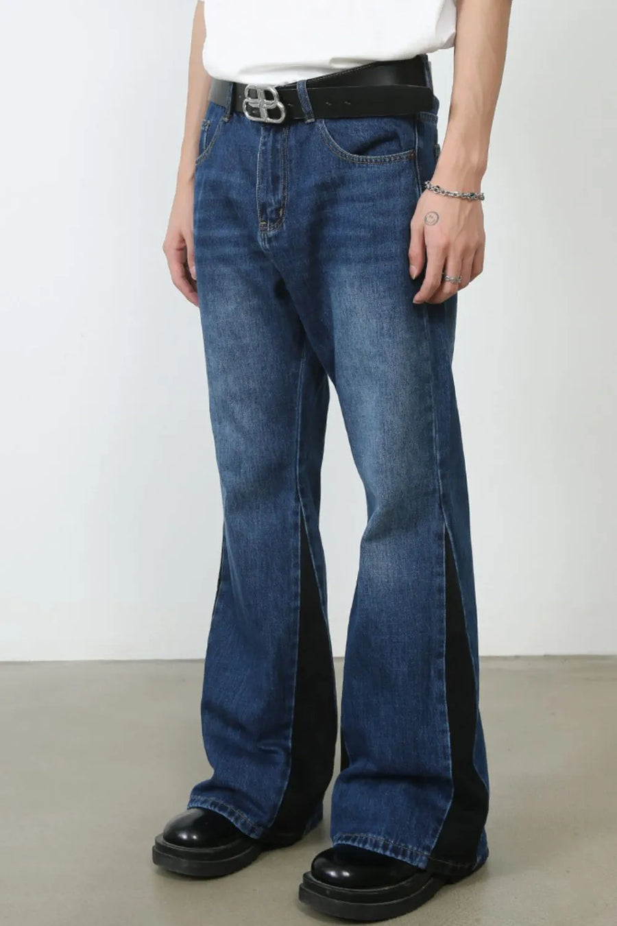 Medium wash denim bootcut trousers with black contrast panels and side slits.