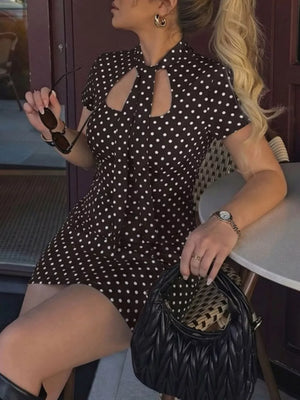 Brown polka dot mini dress with cut-out neckline and short sleeves.
