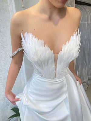 White feather embellished maxi dress with draped skirt and strapless neckline.