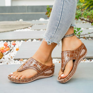 Brown crocodile-embossed wedge thong sandals with gold buckle detail.