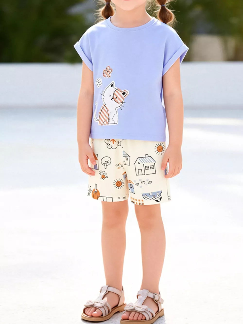 Children's lavender cat graphic t-shirt and cream cartoon house print shorts set.