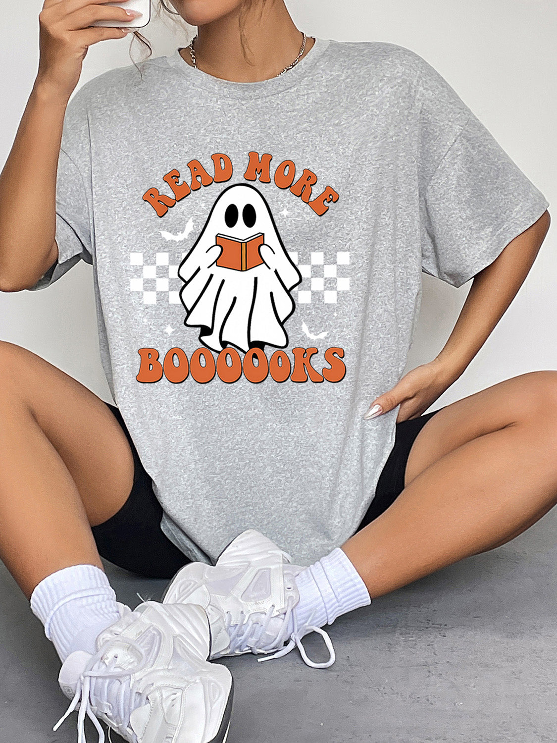 Gray graphic t-shirt with a ghost reading a book and text that says Read More Booookks.