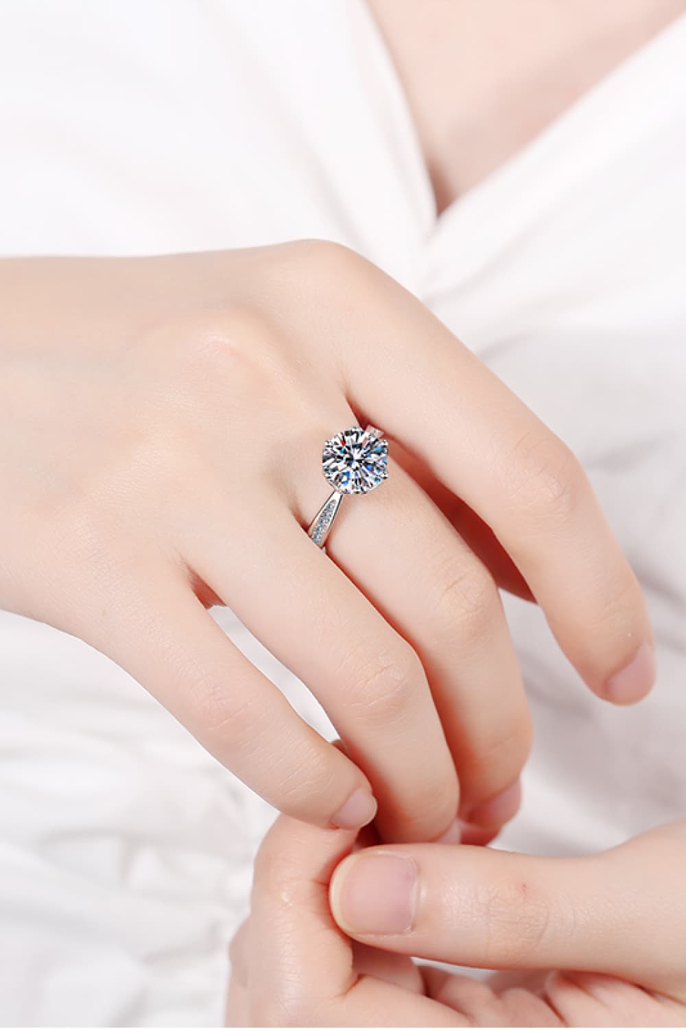 Silver ring with a large round moissanite center stone and pavé band.