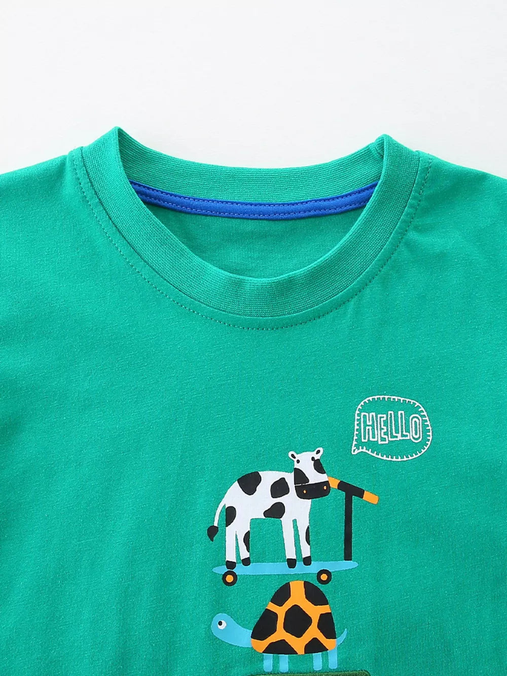 Green cotton toddler tee with cow on scooter and turtle print.