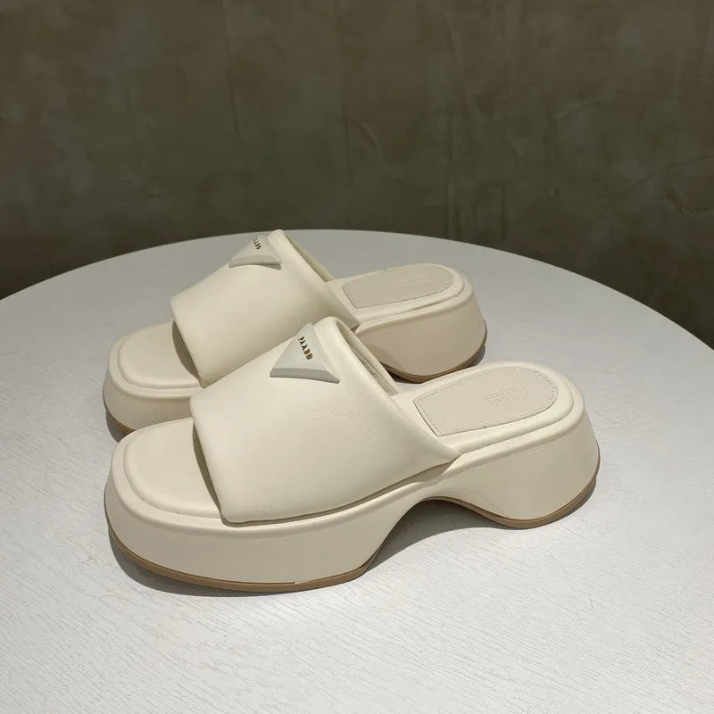 Ivory geometric platform slides with triangular branding detail and chunky heel.