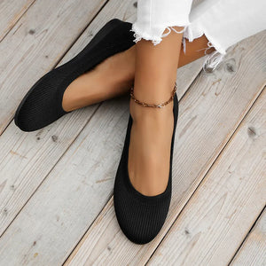 Black textured knit slip-on ballet flats with a round toe and ankle bracelet.