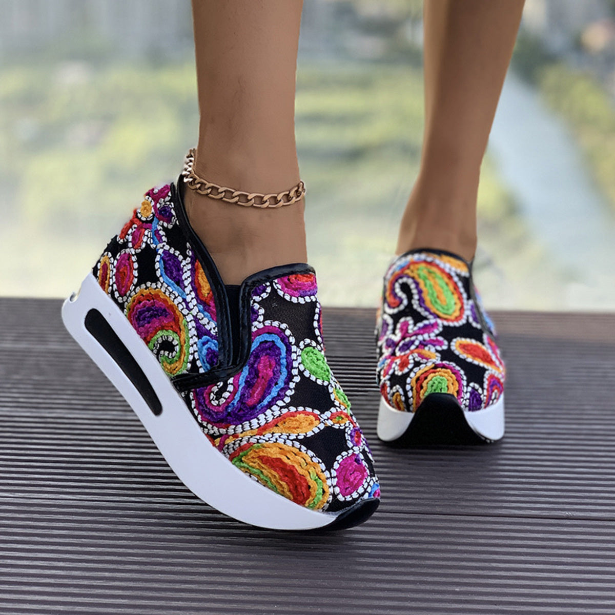 Vibrant slip-on platform sneakers with colorful paisley embroidery and white soles.