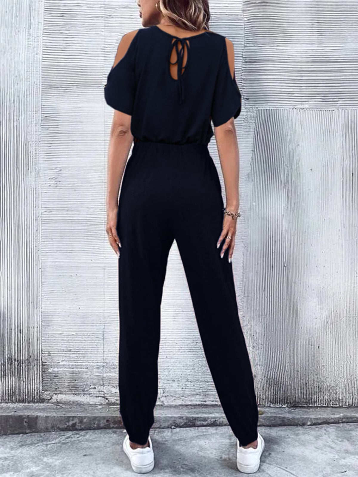 Dark blue cold-shoulder jumpsuit with drawstring waist and tie back detail.