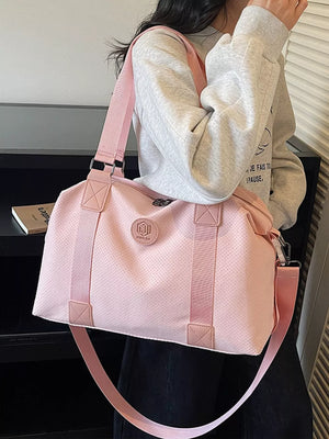 Pink perforated large duffle bag with dual handles and a crossbody strap.